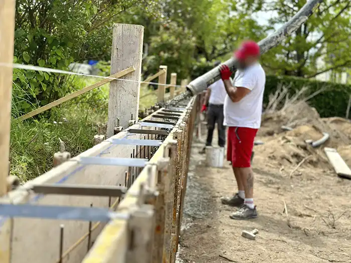 Ouvrier qui coule du béton sur le chantier d'une maison